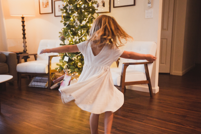 aktywne święta mała dziewczynka tańcząca na tle świecącej choinki